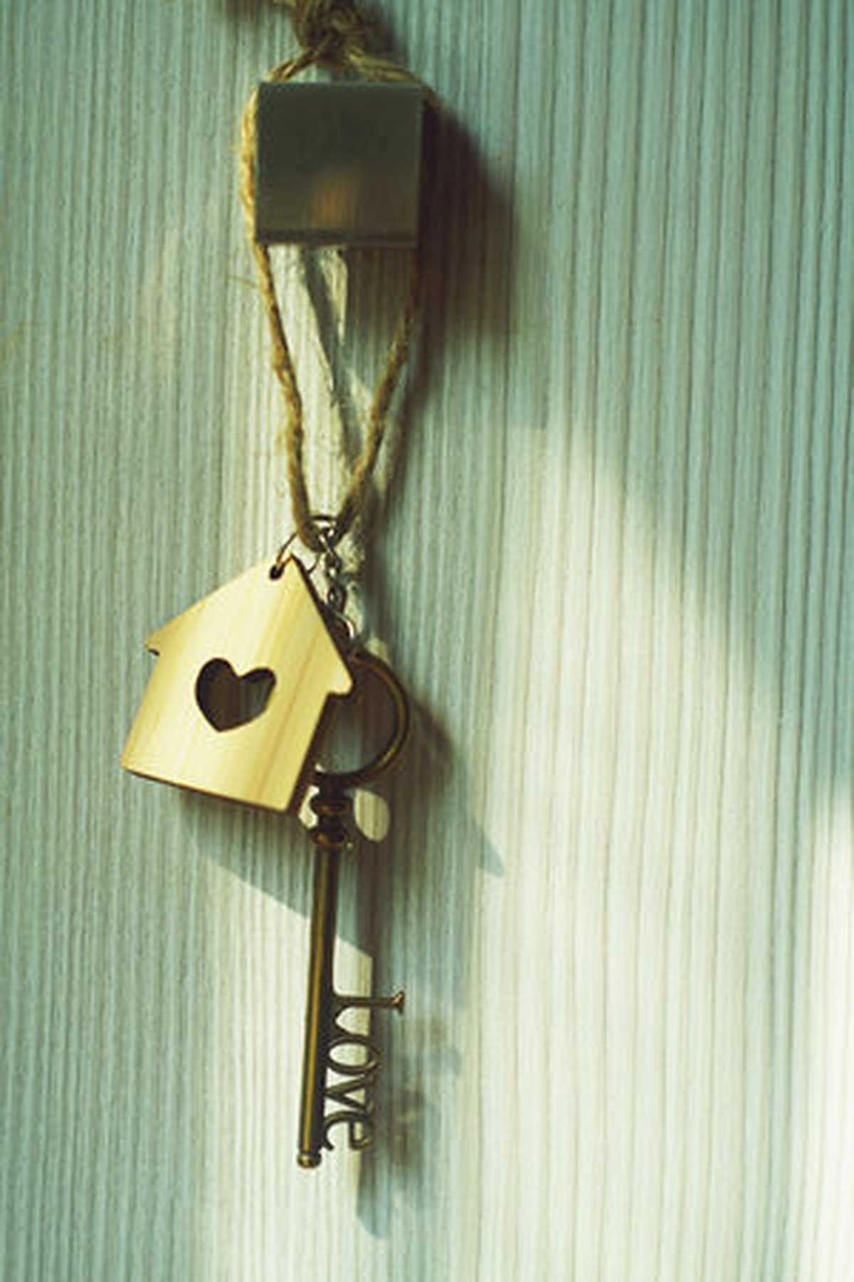 House key with a heart-shaped keychain hanging on a door, a symbol of inherited property